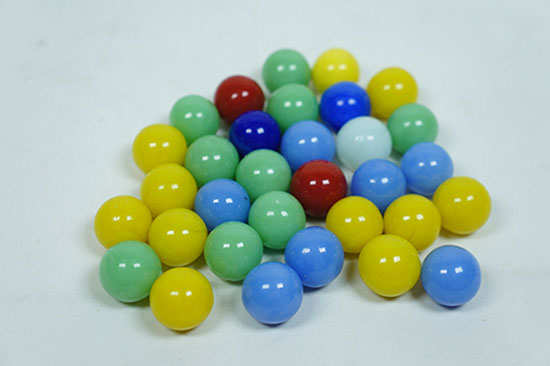a grouping of marbles, all of which are solid colors of varying hues and values.